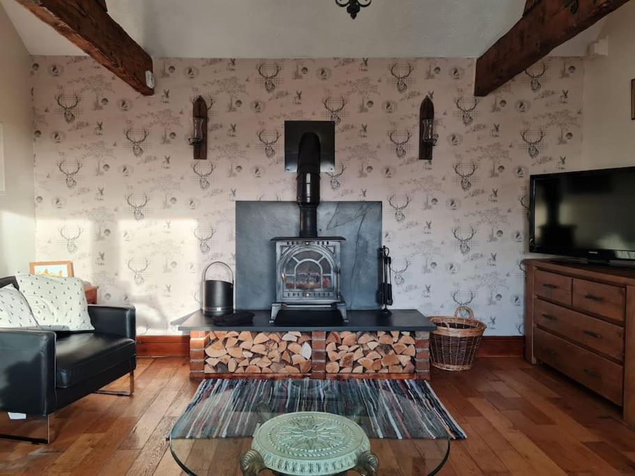 a living room with a fireplace and a tv at Romantic rural cottage, log burner, Sky tv early check in ,large gardens in Llangefni