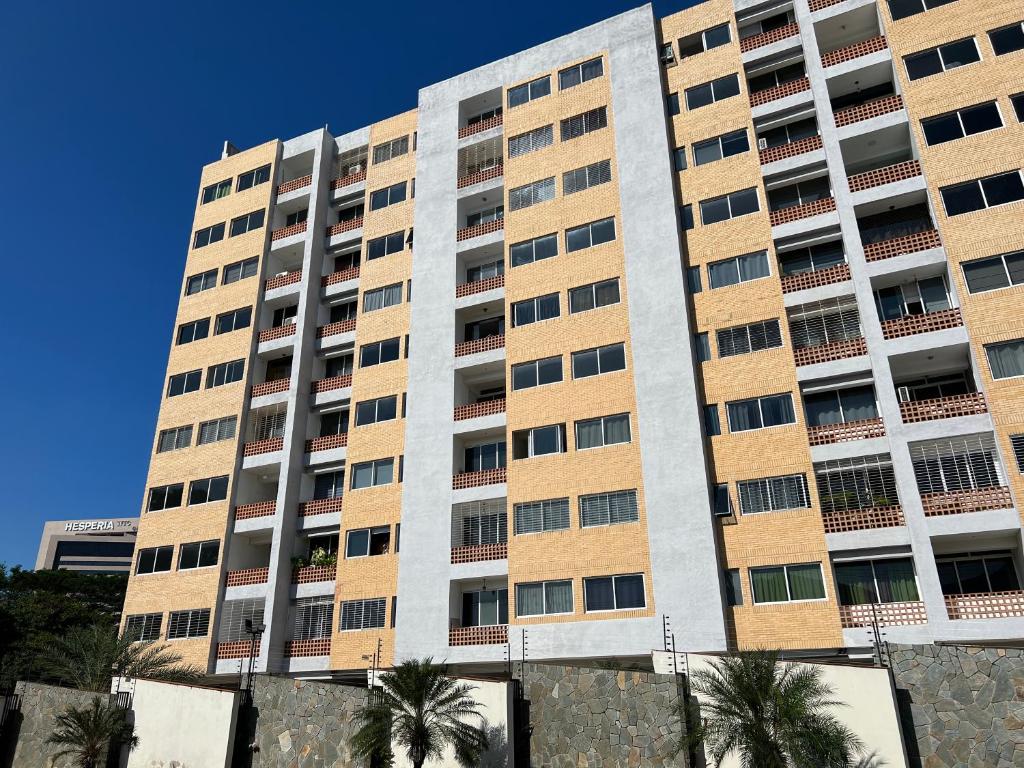 a tall building with palm trees in front of it at Apartamento Diagonal a Hesperia y Dunas in Naguanagua