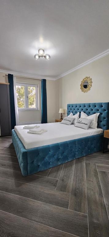 a bedroom with a large bed with a blue headboard at White rezidence II in Curtea de Argeş