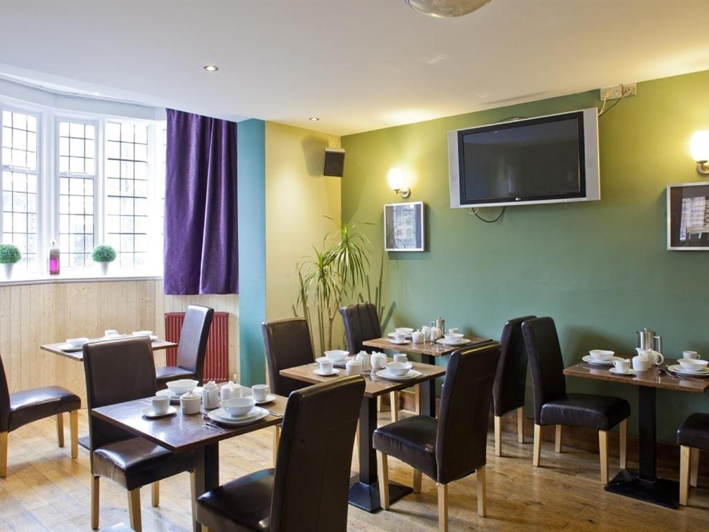 a restaurant with tables and chairs and a flat screen tv at Burton Stone Inn - Free Parking on site in York