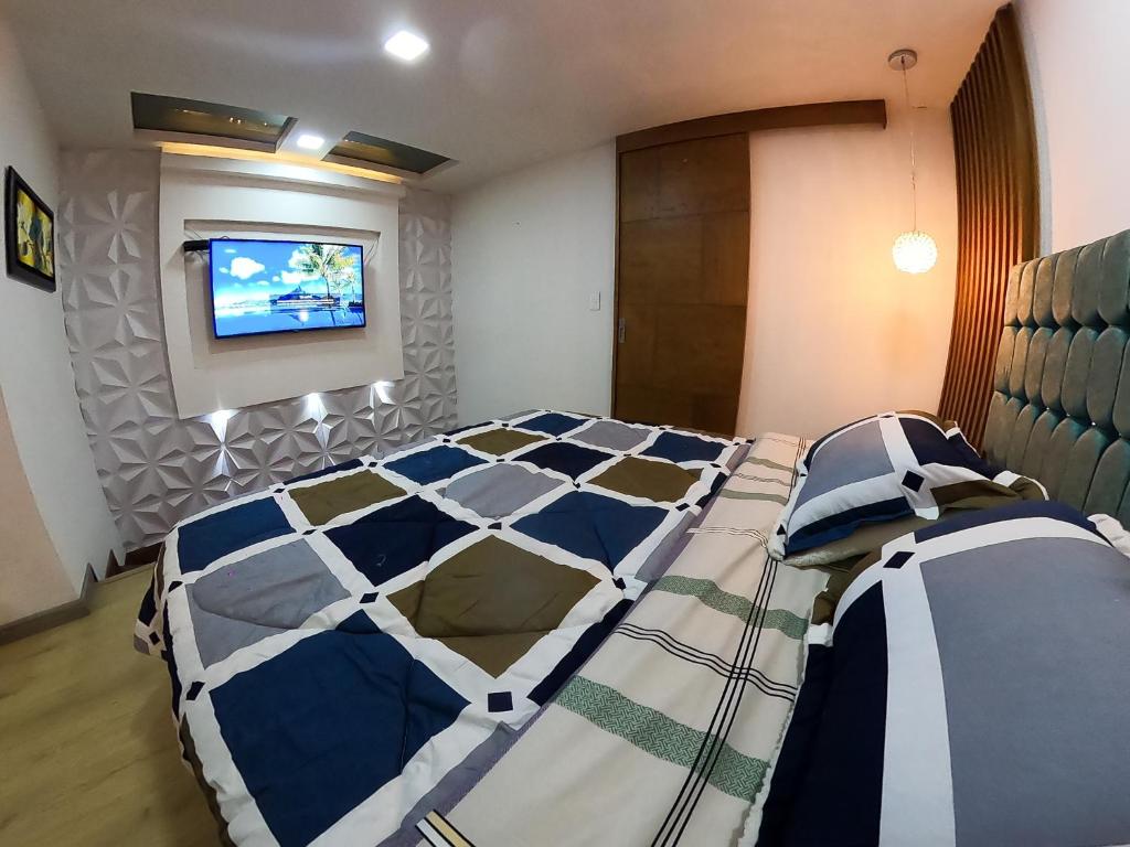 a bedroom with a bed and a tv on a wall at Habitación de lujo in Bogotá