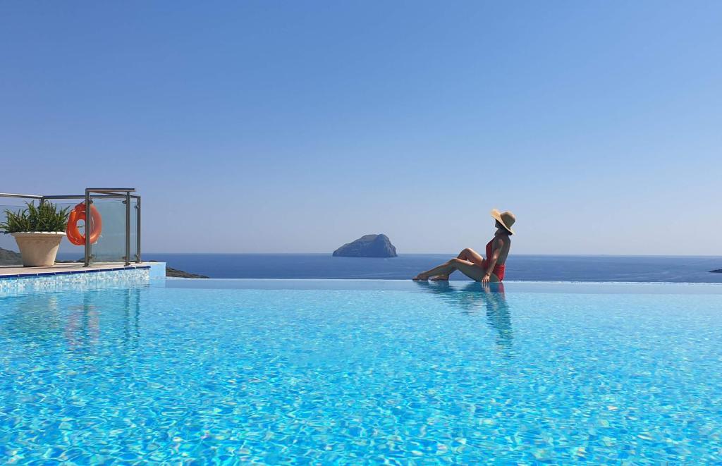 dos personas sentadas en el borde de una piscina en Porto Delfino Retreat en Kapsálion