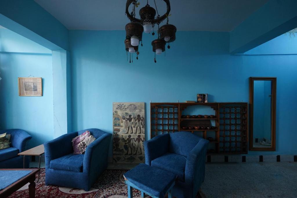 a blue room with two blue chairs and a table at Rose Apartments in Nag` el-Ramla
