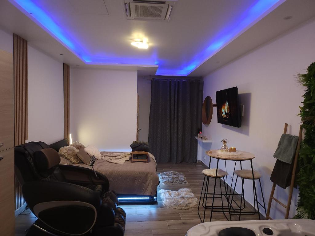 ein Wohnzimmer mit einem Sofa und einem Bett mit blauen Lichtern in der Unterkunft So'Spa appart' jacuzzi & bien-être in Lingolsheim