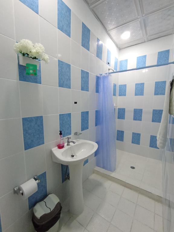 Belo Bay Apartment Hotel في بورتو بيلو: حمام ابيض و ازرق مع حوض و شطاف