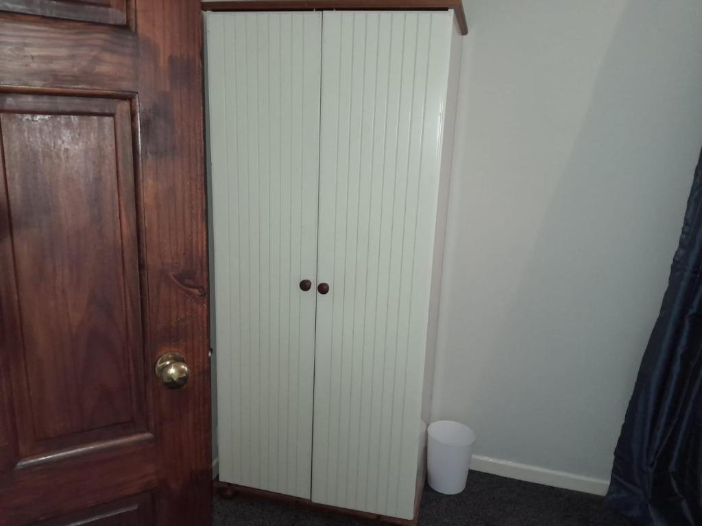 a closet with a door next to a wooden cabinet at Amazing 3 bedroom house with parking. in Nottingham