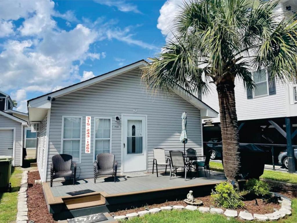 a porch with chairs and a palm tree in front of a house at Beach House in Oceanlakes Campgrounds Myrtle Beach, South Carolina in Myrtle Beach