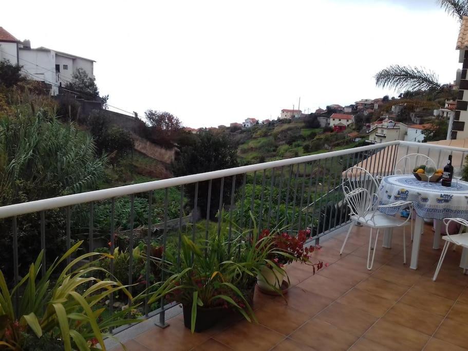 patio con mesa y sillas en el balcón en Casa da Fonte dos Castanheiros en Estreito da Calheta