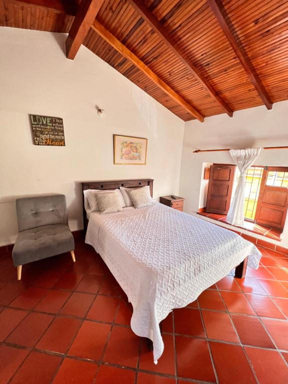 um quarto com uma cama branca e uma cadeira em Real Dream Hostel em San Gil