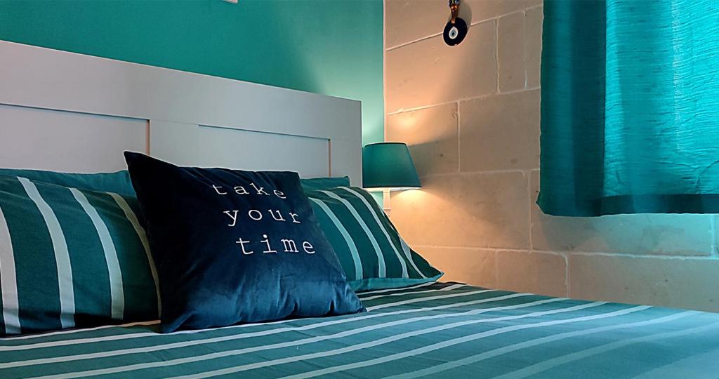 a bed with a pillow that says take your time at Unique New Apartment - Victoria - Gozo in Victoria