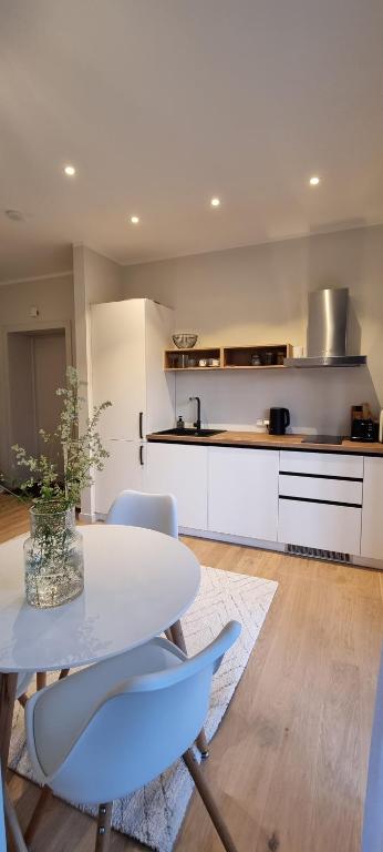 cocina blanca con mesa blanca y sillas en Albatross Green Apartment, en Ķesterciems