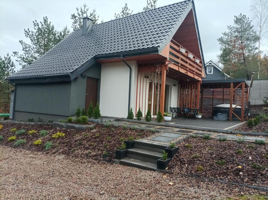 een huis met een gambrel dak en een patio bij ,,Domek Na Skarpie'' z Balią i basenem letnim in Sulęczyno