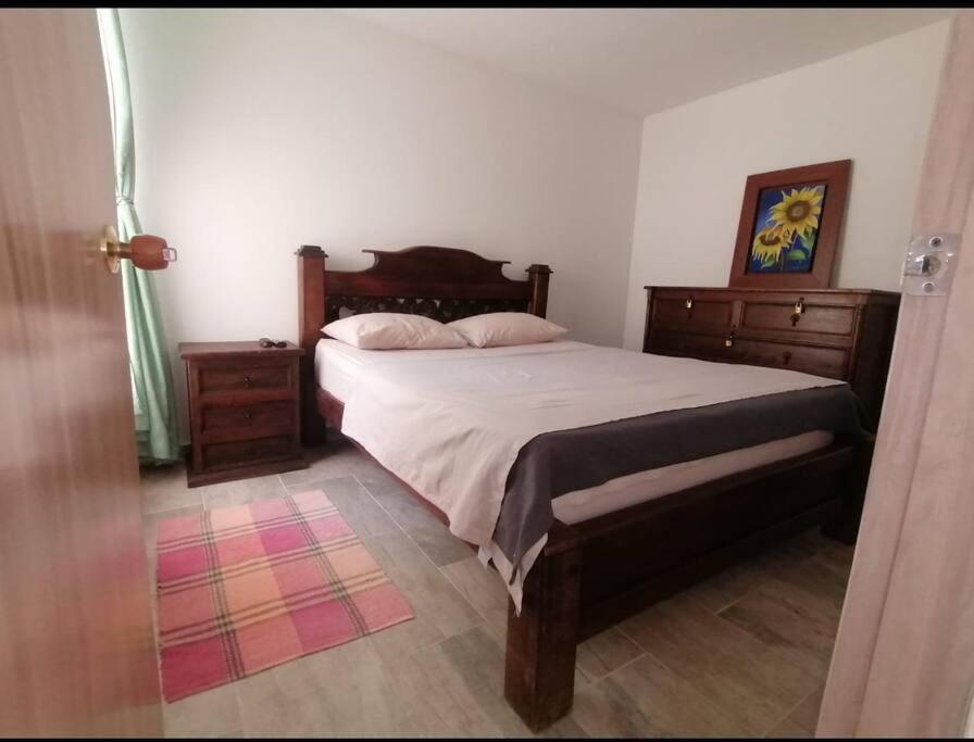 a bedroom with a large bed with wooden furniture at Comodidad y tranquilidad in Ibagué