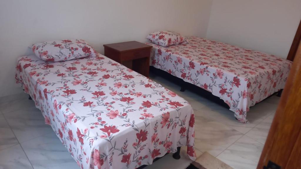 a bedroom with two beds with red and white covers at Suítes da Alcy in Caraíva