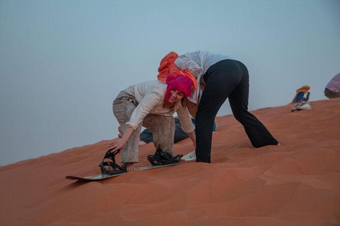 dos mujeres de pie en una tabla de snowboard en el desierto en Erg Chigaga Camp Shooting Stars, en Mhamid