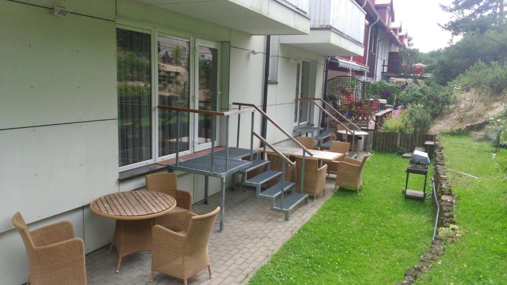 d'une terrasse avec une table, des chaises, une table et de la pelouse. dans l'établissement Nakvynė pas Romą, à Nido