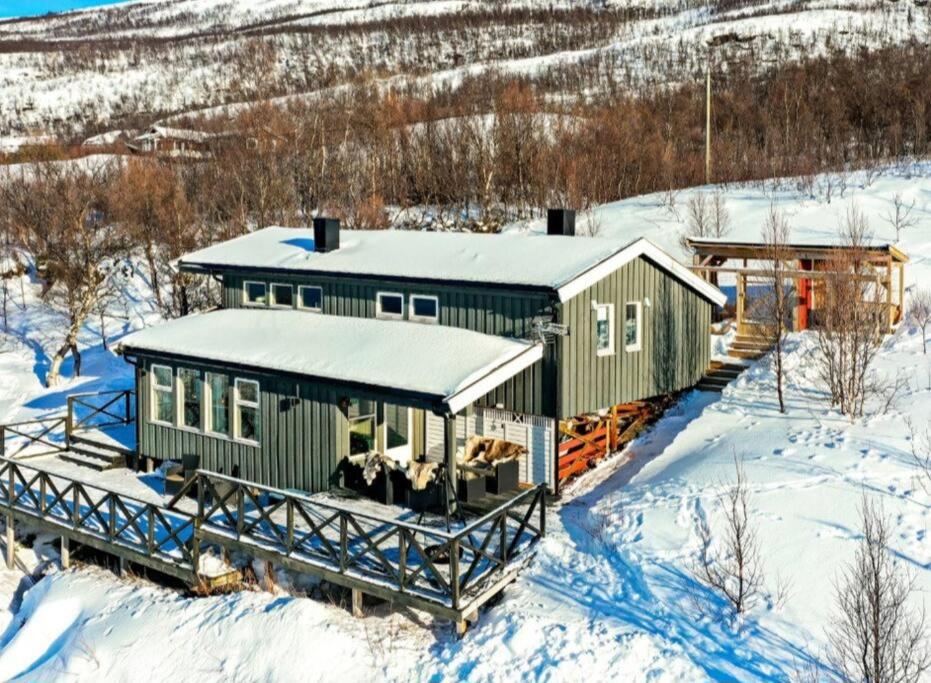 una casa verde en la nieve con nieve en Hytte paradis i Kviby, en Kviby