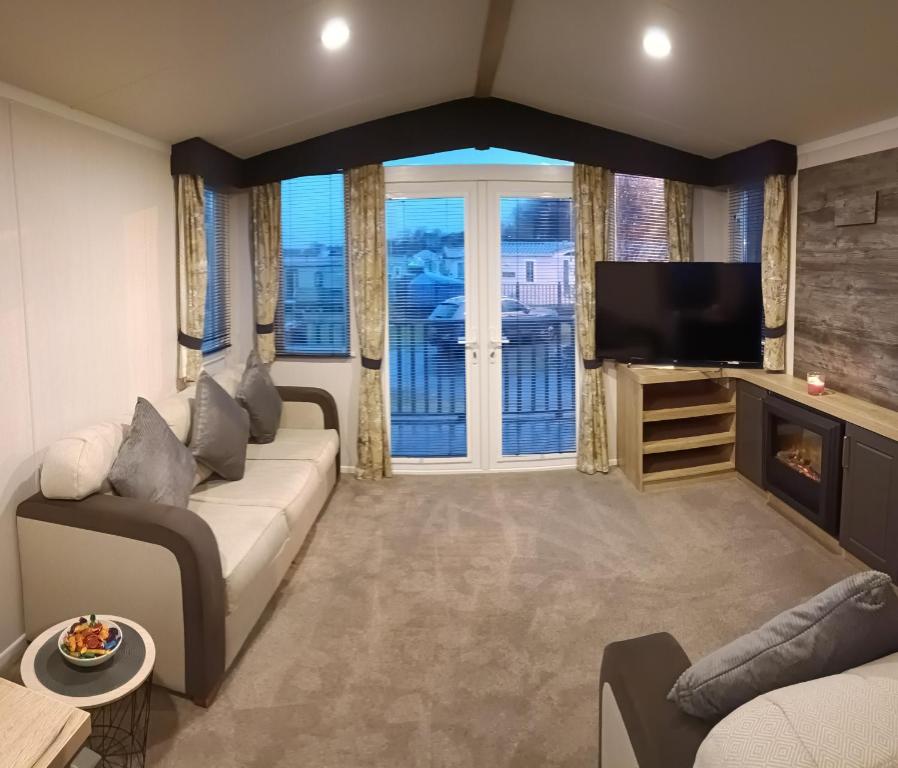 a living room with a couch and a tv at Hillingworth's Hot Tub Retreat - Lochmaben in Dumfries