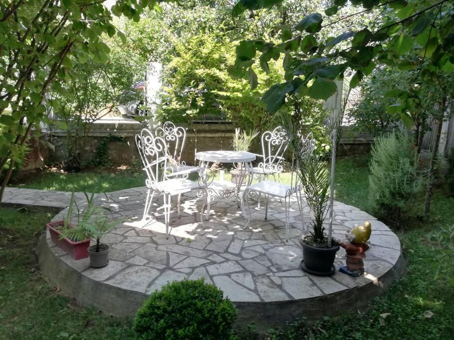 eine Terrasse mit einem Tisch und Stühlen im Garten in der Unterkunft Apartment Milinkovic in Kovanluk