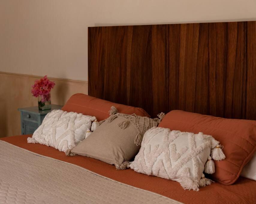 Una cama con almohadas naranjas y blancas. en Casa Lilia, ubicada en el Centro Histórico, en Campeche
