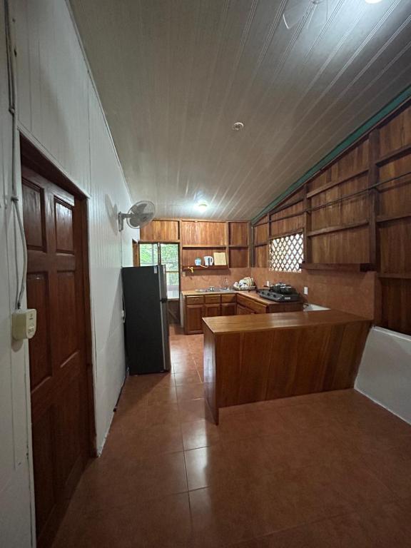 kuchnia z drewnianymi szafkami i czarną lodówką w obiekcie Casa Oasis de Ballenas w mieście Uvita