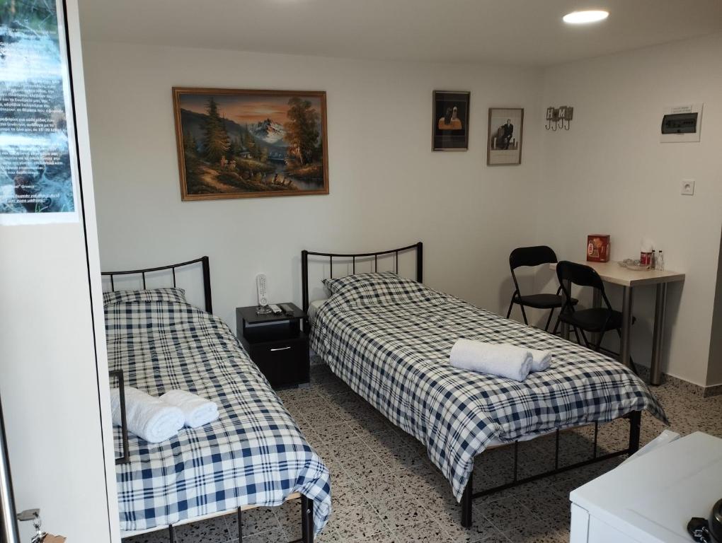 a bedroom with two beds and a table and a mirror at Ξενώνας museum ισόγειο στο Ελληνικό Ιωαννίνων in Kalentzi