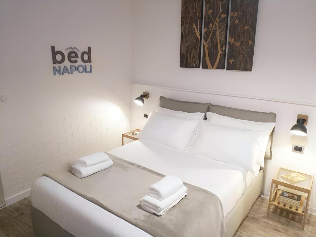 un letto bianco con due asciugamani sopra di Bed Napoli a Napoli
