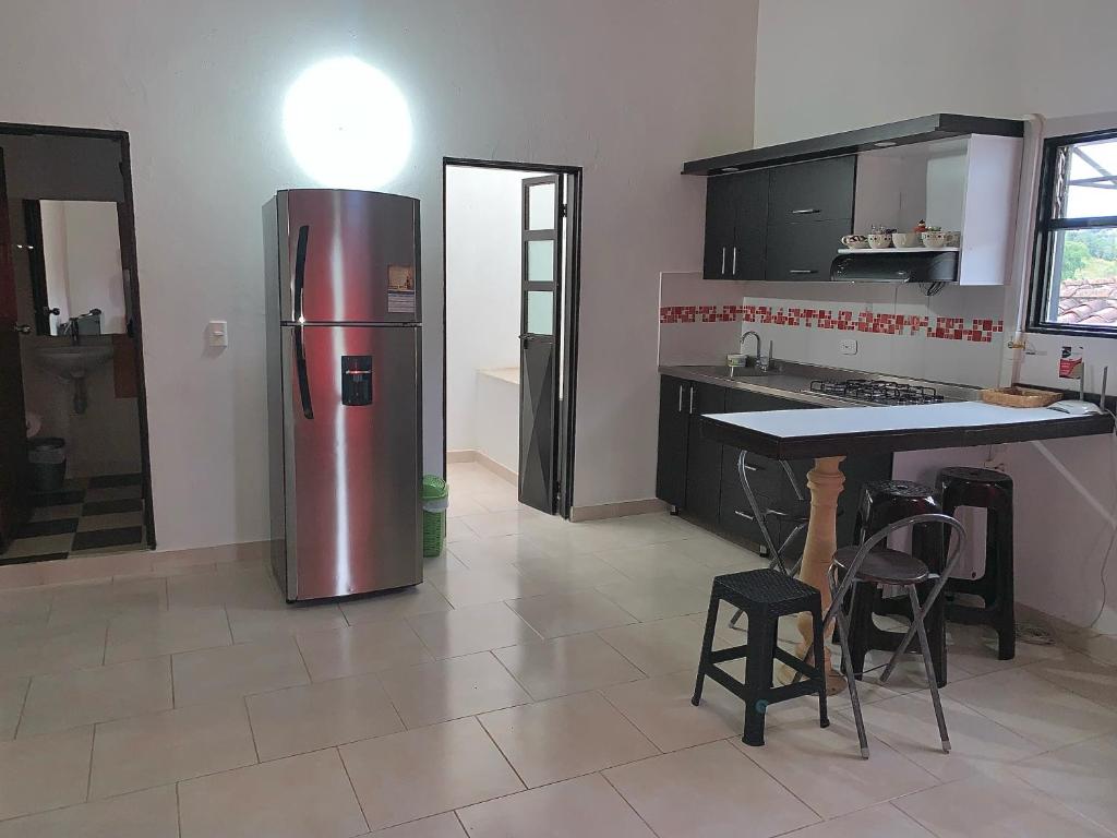 a kitchen with a stainless steel refrigerator and a table at Balcones de la Casona in Guatapé