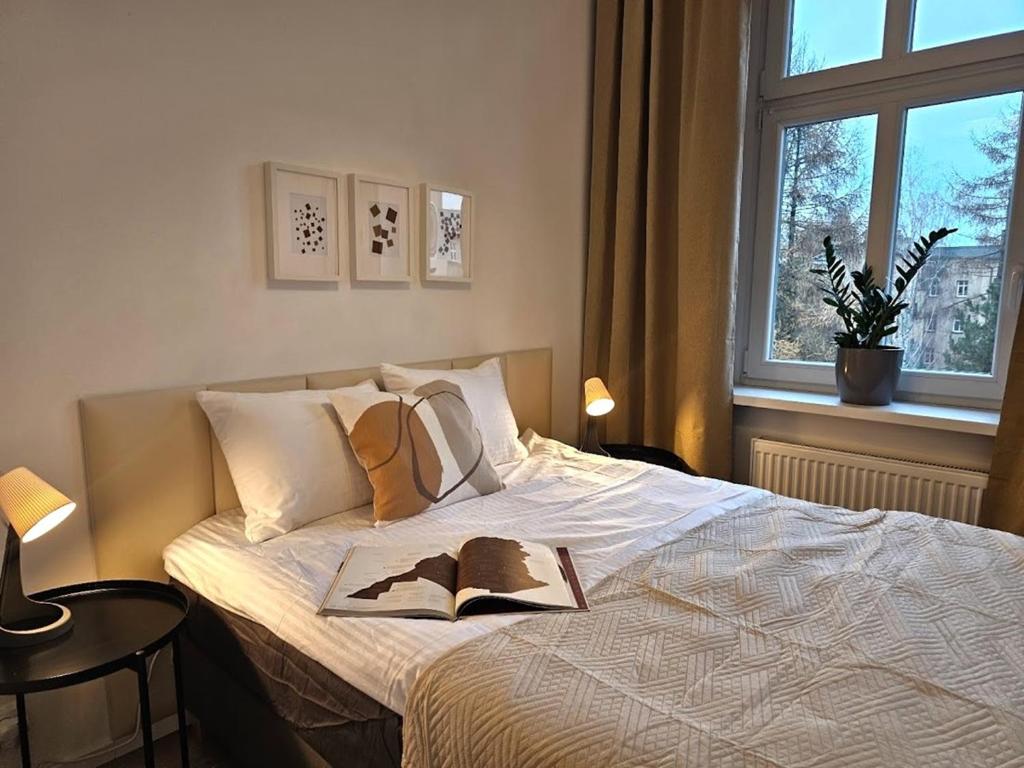 ein Schlafzimmer mit einem Bett mit einem Buch darauf in der Unterkunft URBAN APARTMENTS PREMIUM No12 Chorzów, Katowice with PRIVATE PARKING in Chorzów