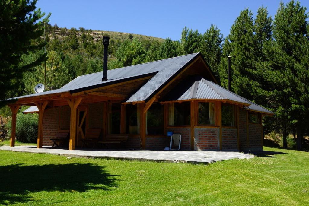 Cabaña de madera con techo en un campo de césped en Estancia La Esperanza en San Carlos de Bariloche