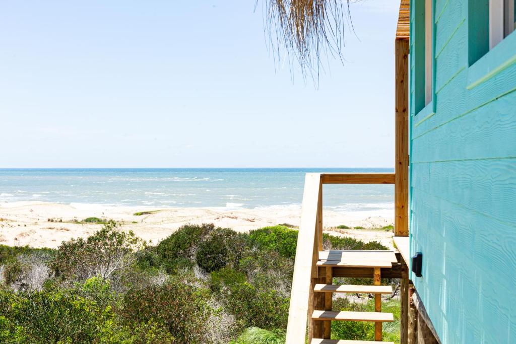 a blue house with a staircase leading to the beach at Cabaña Agua de Mar in Punta Del Diablo