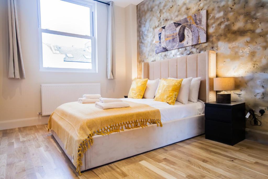 a bedroom with a bed with yellow pillows and a window at Luxury Fulham 3 bedroom Garden House in London