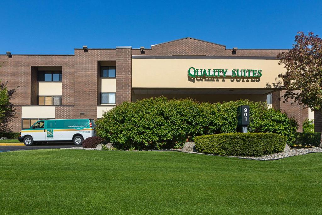 a building with a van parked in front of it at Quality Suites in Lansing