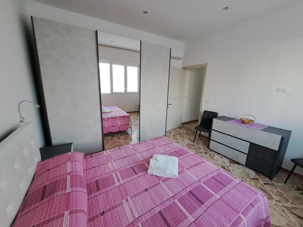1 dormitorio con cama rosa y espejo en B&B Al Centro, en Presicce