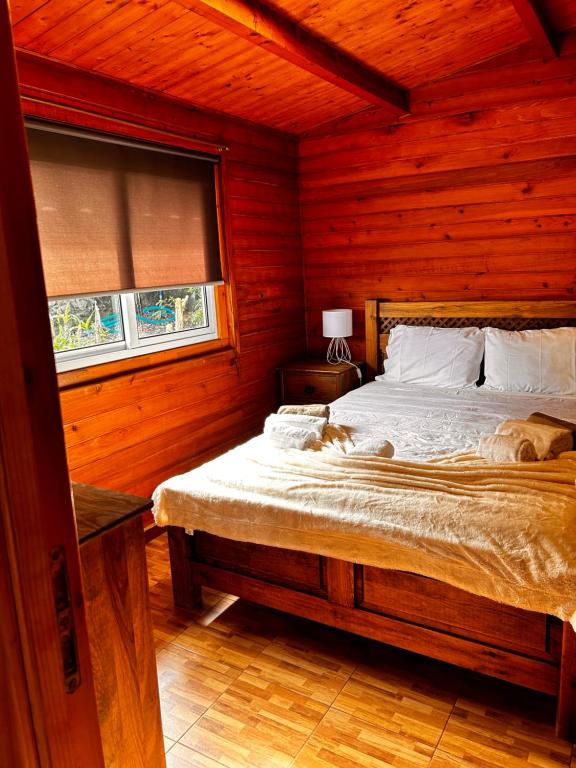 a bedroom with a bed in a wooden room at Vila Emigrante in Capelas