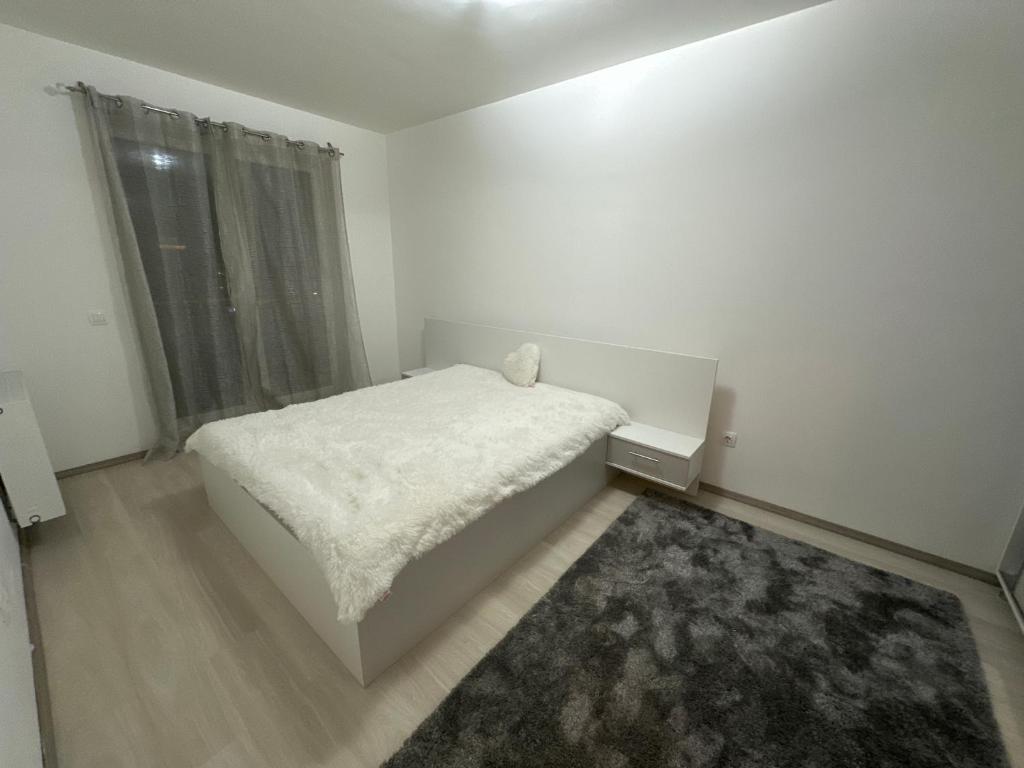 a white bedroom with a bed and a window at Regim hotelier in Braşov