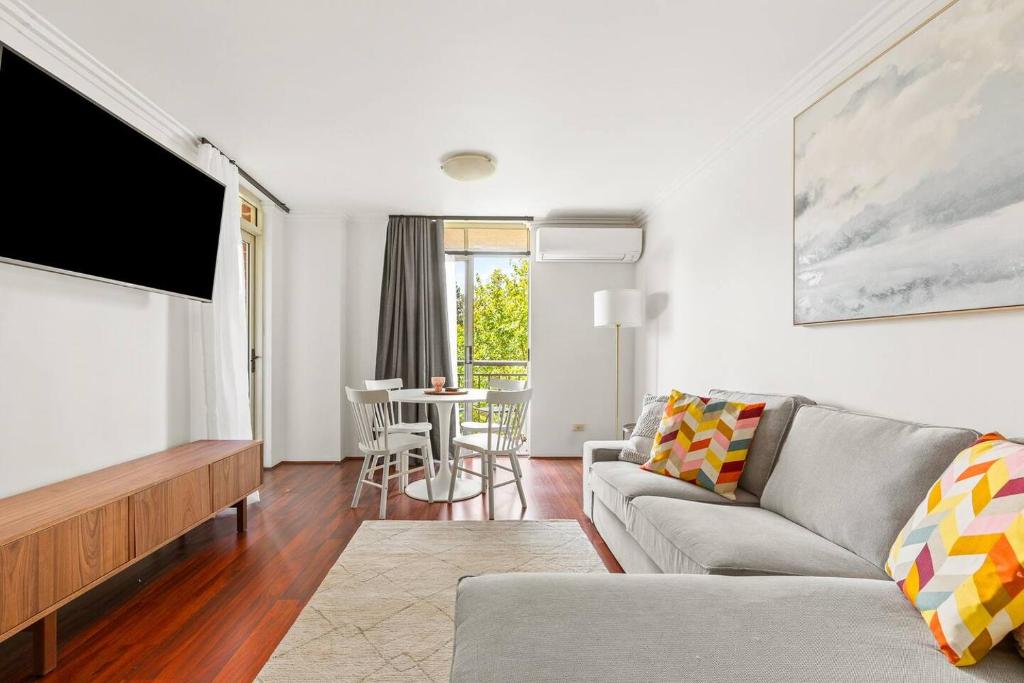 a living room with a couch and a flat screen tv at 'Woolloomooloo Wonder' A Sydney Work-Play Hideout in Sydney