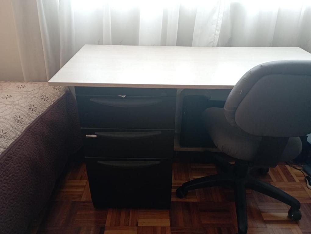 a desk with a chair next to a bed at Habitación acogedora in Quito