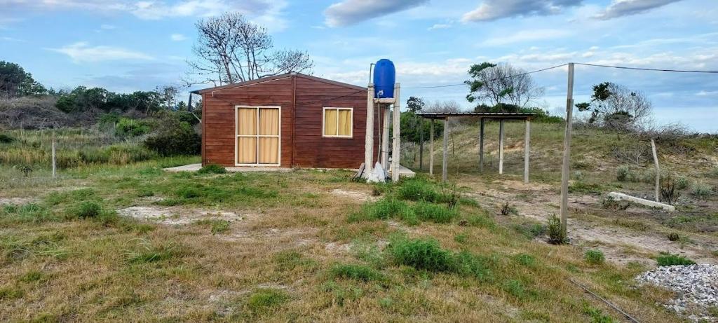 uma pequena casa num campo com um barril azul em Merencere La Esmeralda, Monoambiente a pasos de la playa em La Esmeralda
