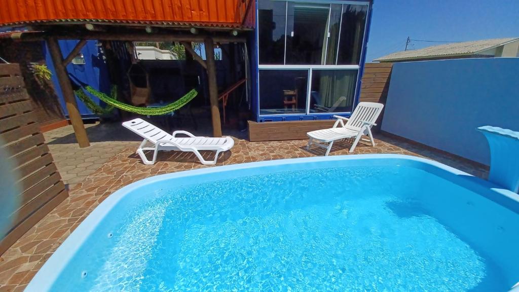 a pool with two chairs and a hammock next to a house at Hostel Tribos Livres in Torres