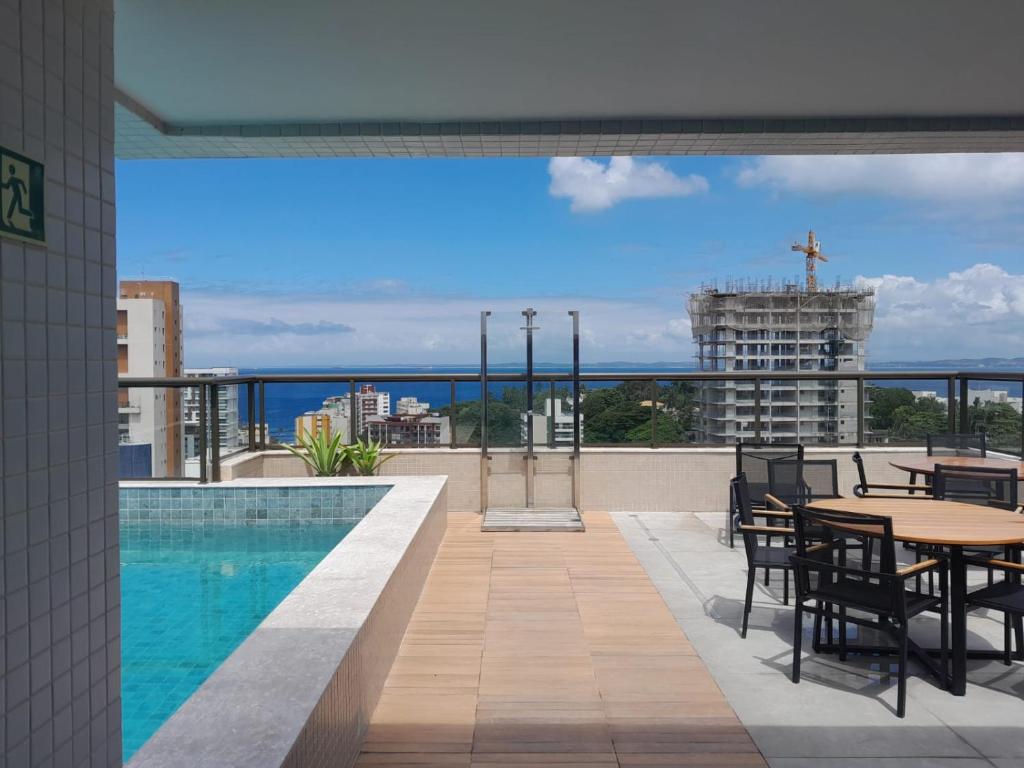 een balkon met een tafel en stoelen en een zwembad bij Barra Caravela Studio in Salvador