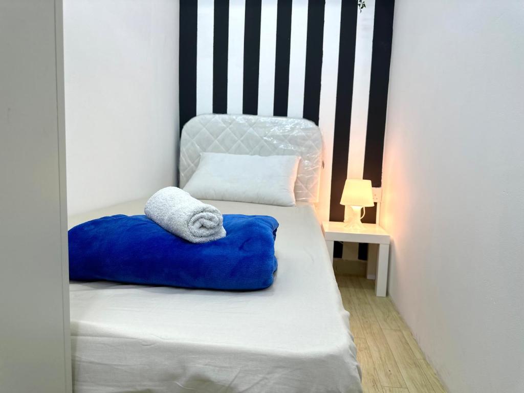 a bed with a blue pillow and a chair at Striped Partition Room in Barsha 1 Near Mall of the Emirates in Dubai