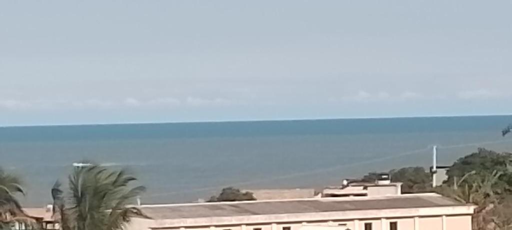 uma vista para um edifício com o oceano ao fundo em Lugar de paz! em Marataízes