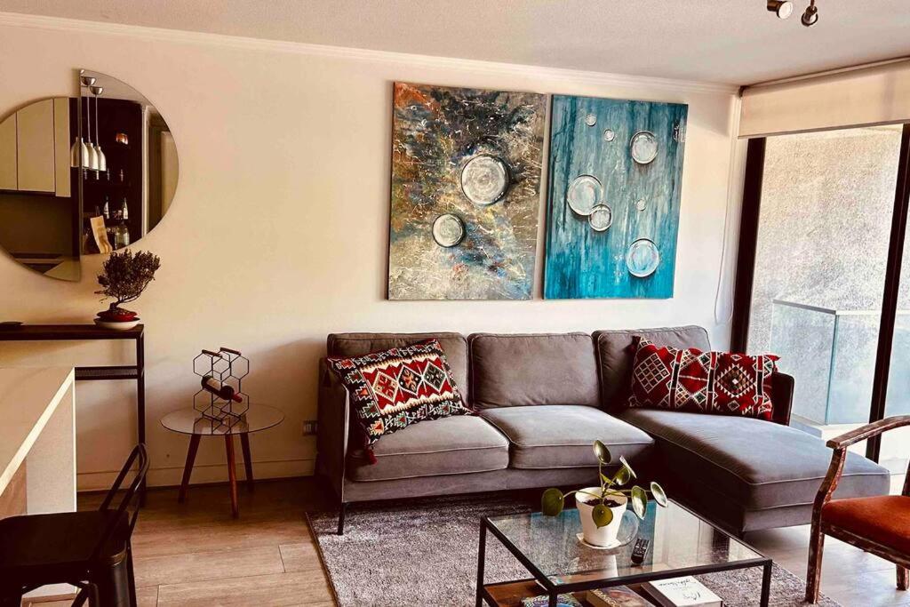 ein Wohnzimmer mit einem Sofa und einem Gemälde an der Wand in der Unterkunft Apartamento en Las Condes frente a parque araucano in Santiago
