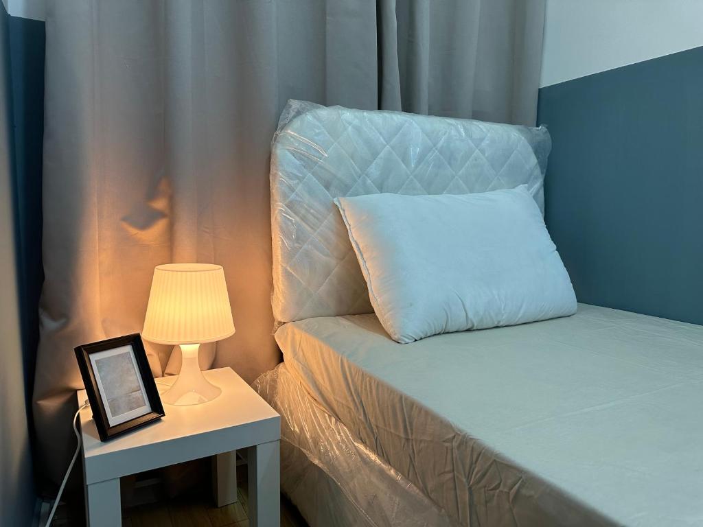 a bed with a pillow next to a table with a lamp at Spacious Mini Partition Room Near Emirates Mall in Dubai