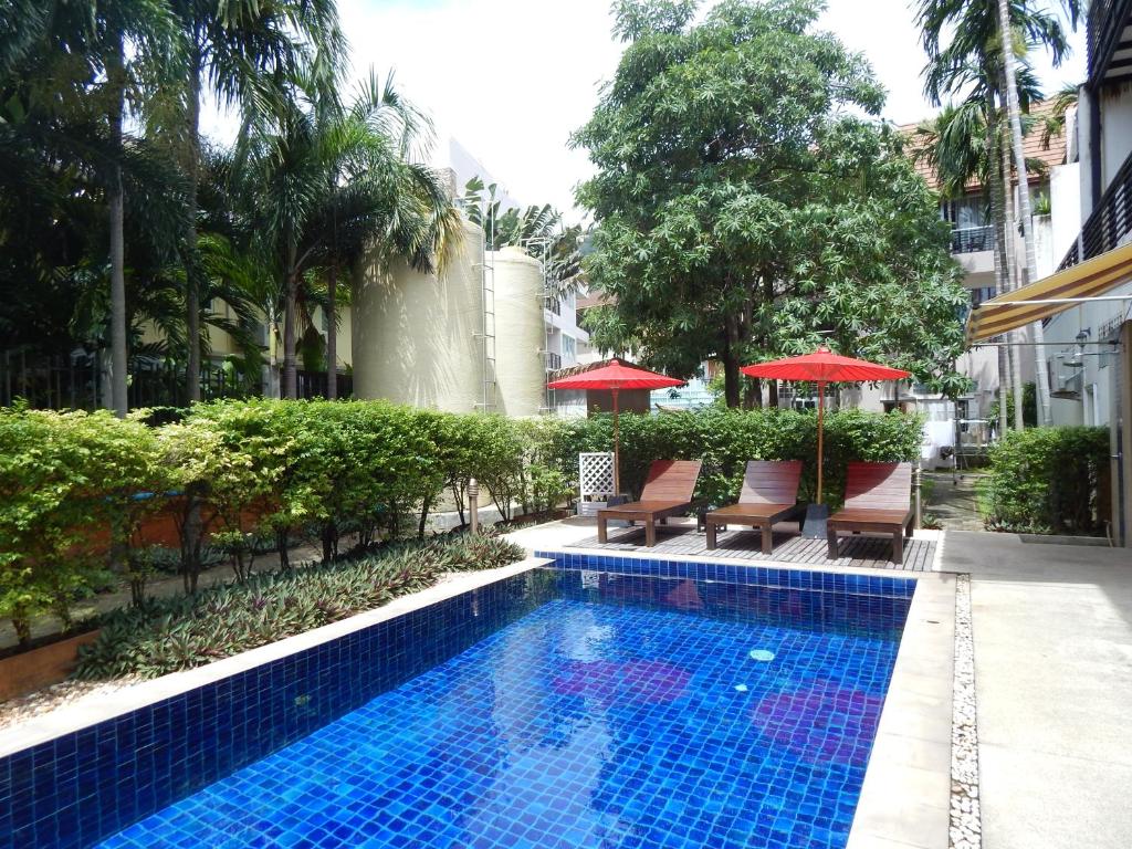 a swimming pool with chairs and umbrellas next to a building at Jinta Andaman in Kata Beach