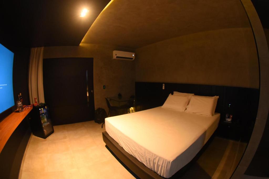 1 dormitorio con 1 cama blanca en una habitación oscura en All in Motel, en Garanhuns