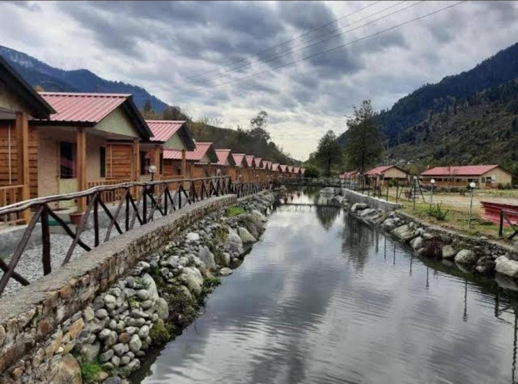 The Shivalaya Retreat - A River Side Resort في Jagatsukh: نهر امام مجموعة منازل