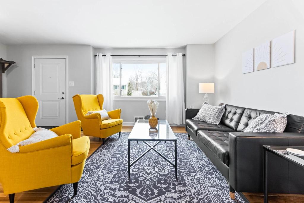 a living room with a black couch and yellow chairs at The Cranbrook- Close to OSU-Downtown Columbus-Short North-Clintonville-Upper Arlington in Columbus