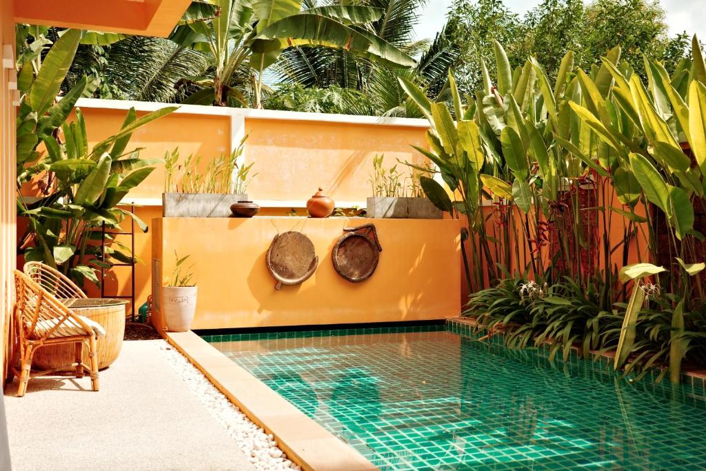 uma piscina num jardim com plantas em The Orange Villa Near Beach 海灘附近的家庭別墅 em Praia de Kamala